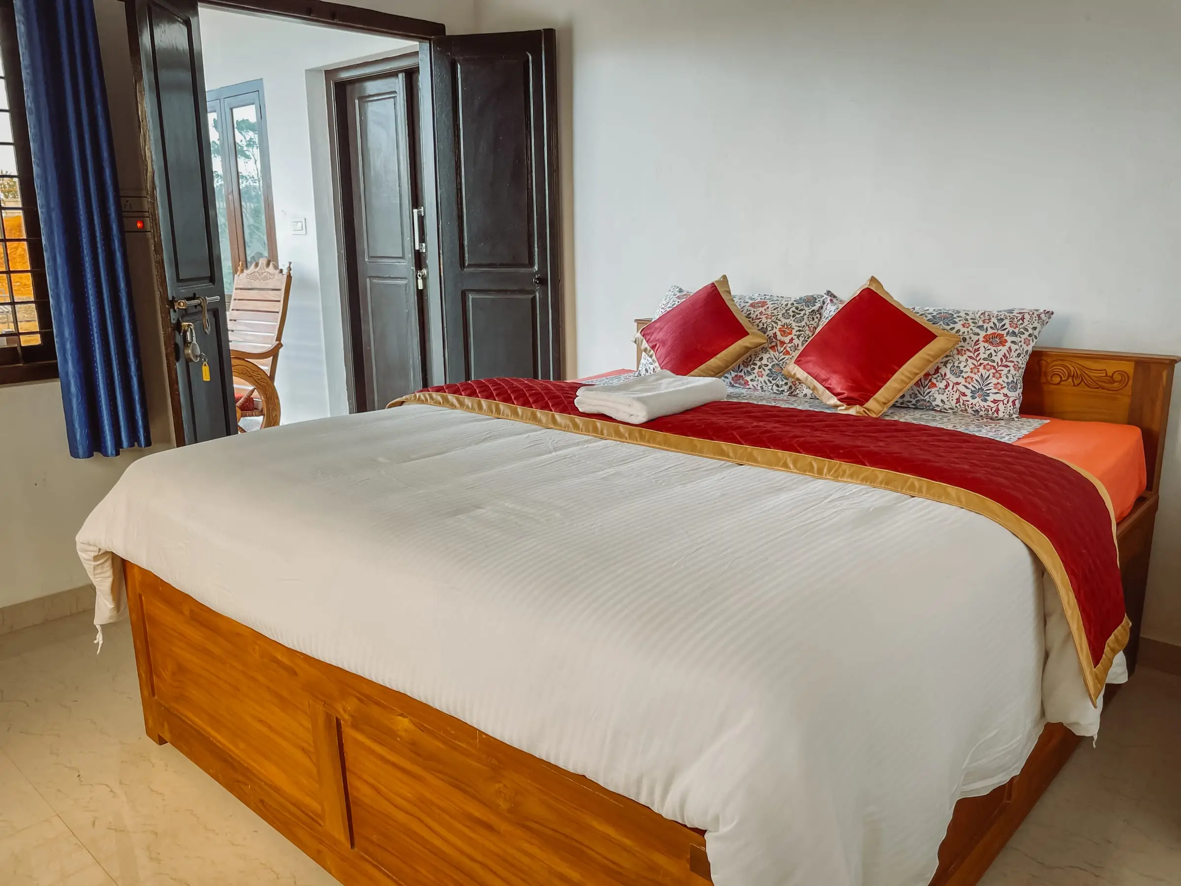 The Cozy Room: bed made up with red cushions, wardrobe beside it