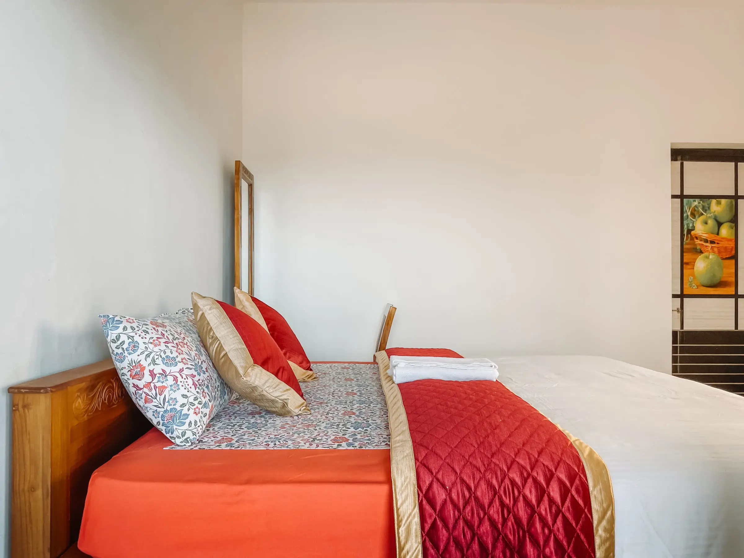 The Cozy Room: bed against a white wall with a mirror