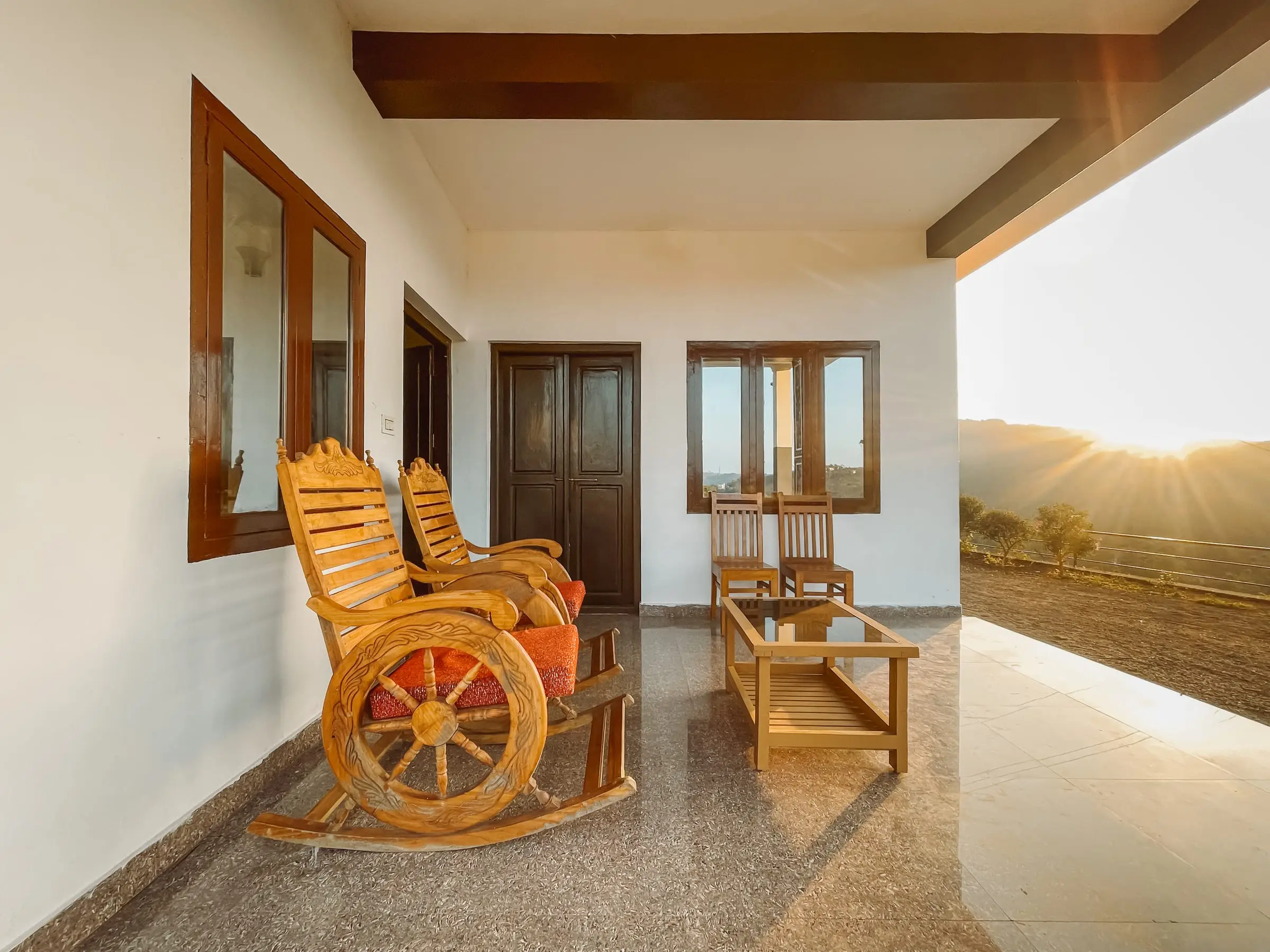 Wooden rocking chairs on the tiled verandah as the sun sets over the hills