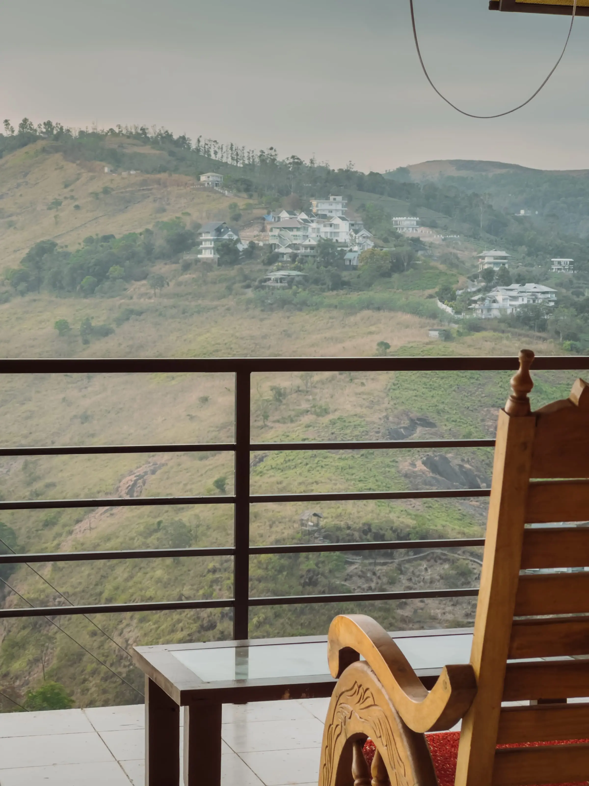 A rocking chair on the balcony facing the green valley